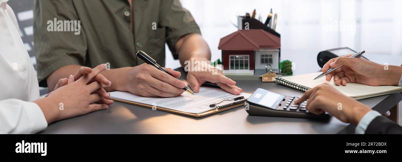 Panorama view of married couple signing house loan contract with real