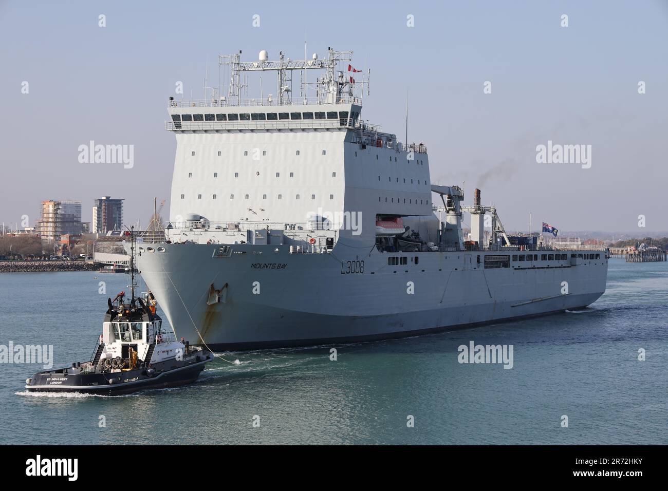 The tug SD INDULGENT ahead of the Royal Fleet Auxiliary landing ship dock RFA MOUNTS BAY as the Bay class vessel departs from the Naval Base Stock Photo
