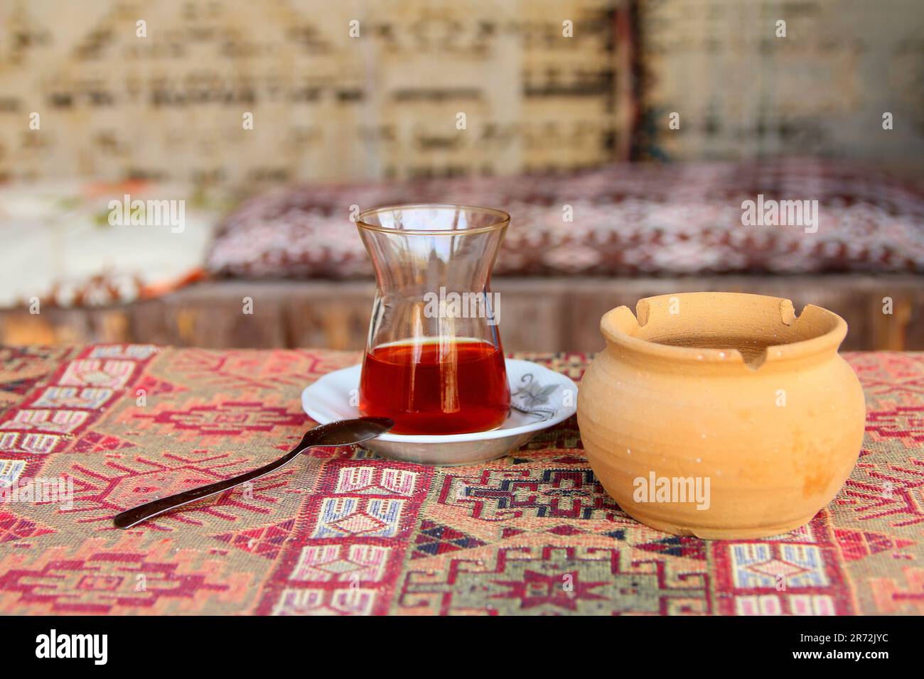 Photo taken in Turkey. The picture shows a small glass of strong tea called - armouts on a traditional Turkish rug spread out on the table. Near a pot Stock Photo