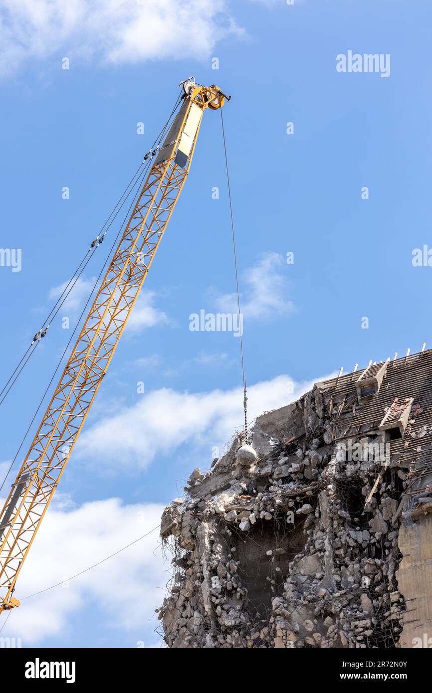 Heavy wrecking ball crane demolishing old building against blue sky in Magdeburg Germany. Building dismantling and construction waste disposal Stock Photo