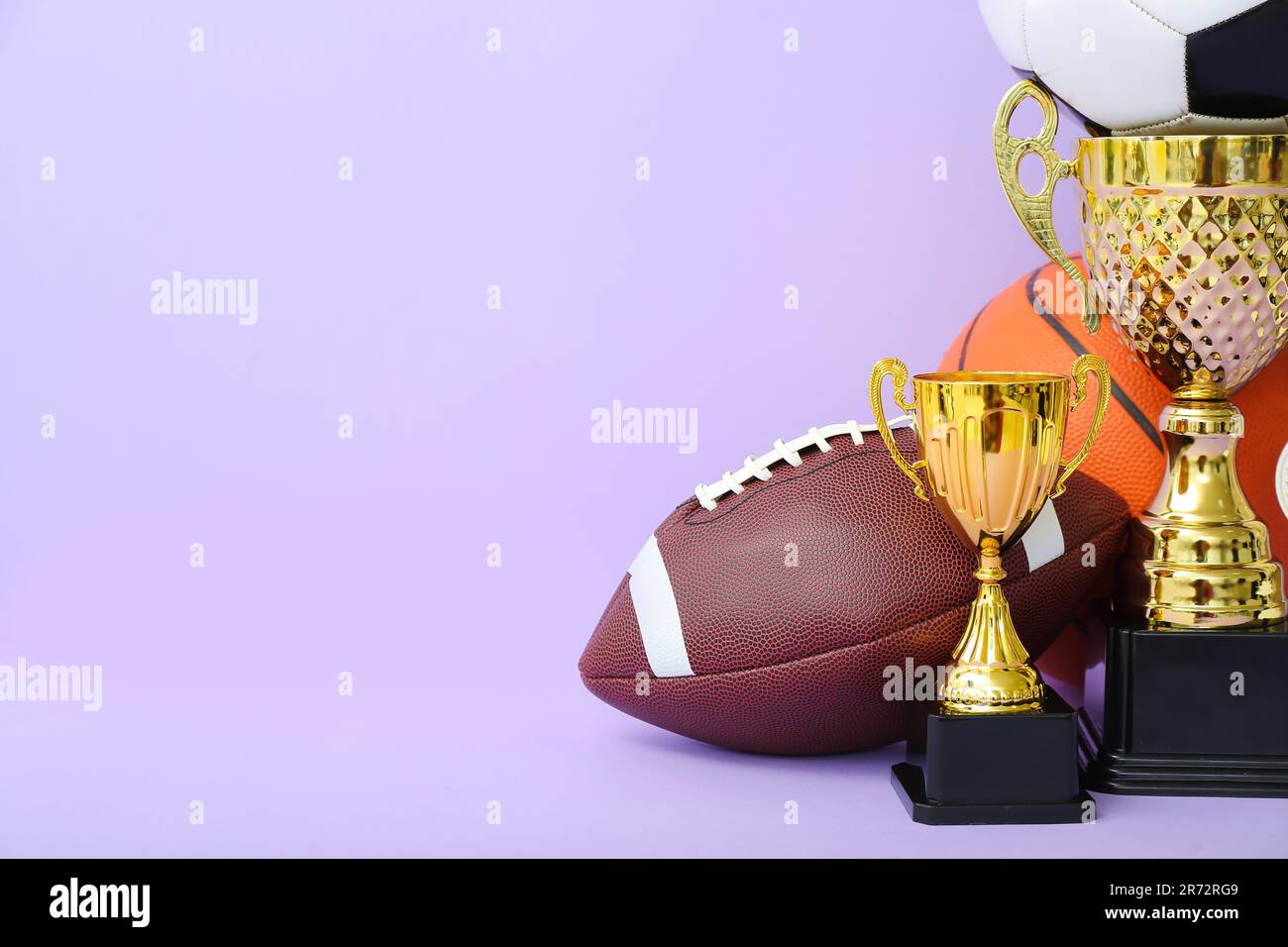 Gold cups with balls on lilac background Stock Photo