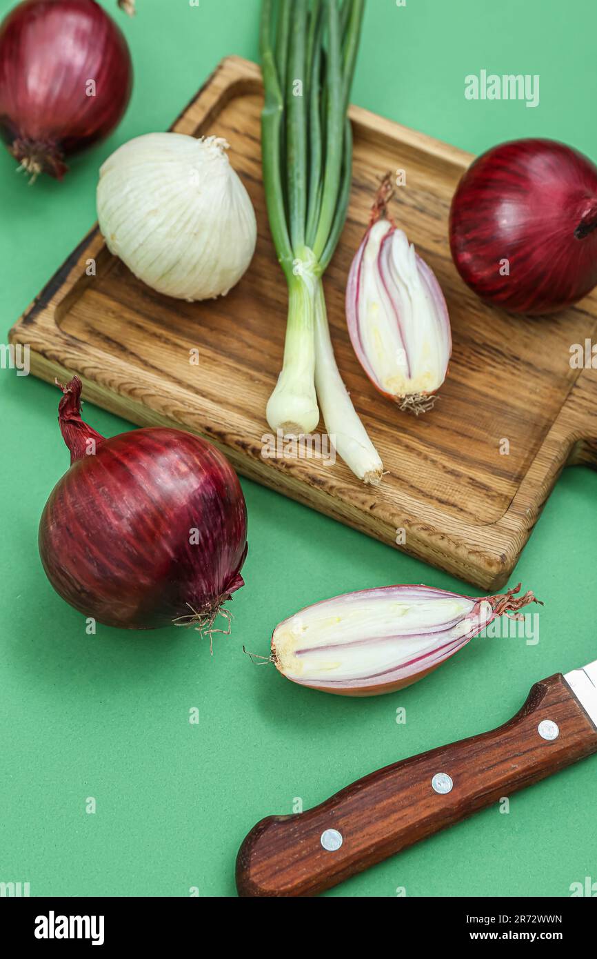Wooden board with different kinds of onion on green background Stock ...