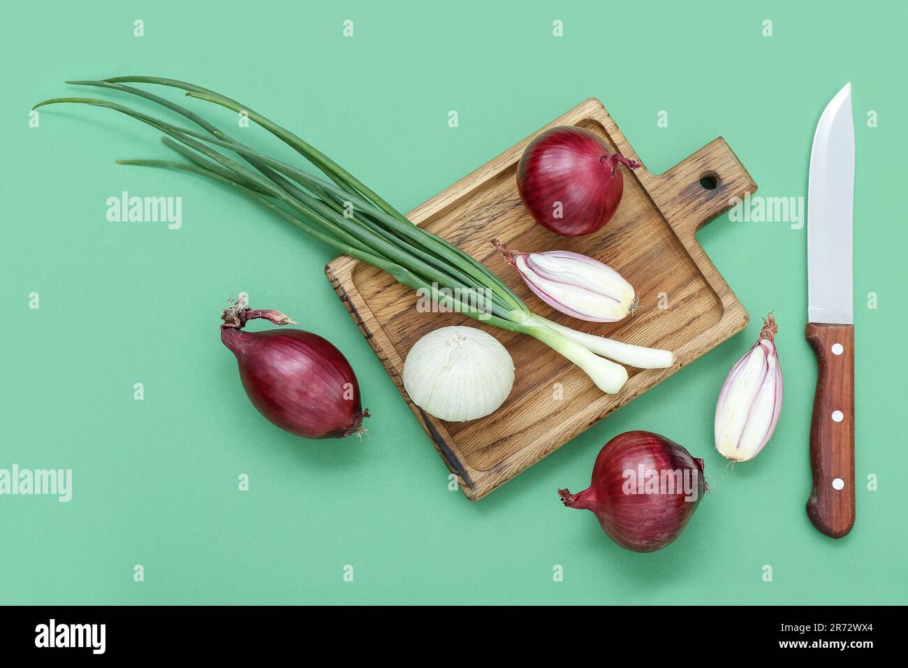 Wooden board with different kinds of onion on green background Stock ...