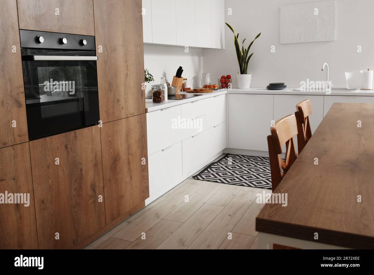 Interior of light kitchen with white counters, island and integrated ...