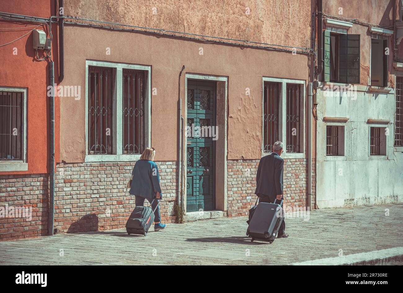 Unidentified middle age tourist couple carrying their baggage trolley