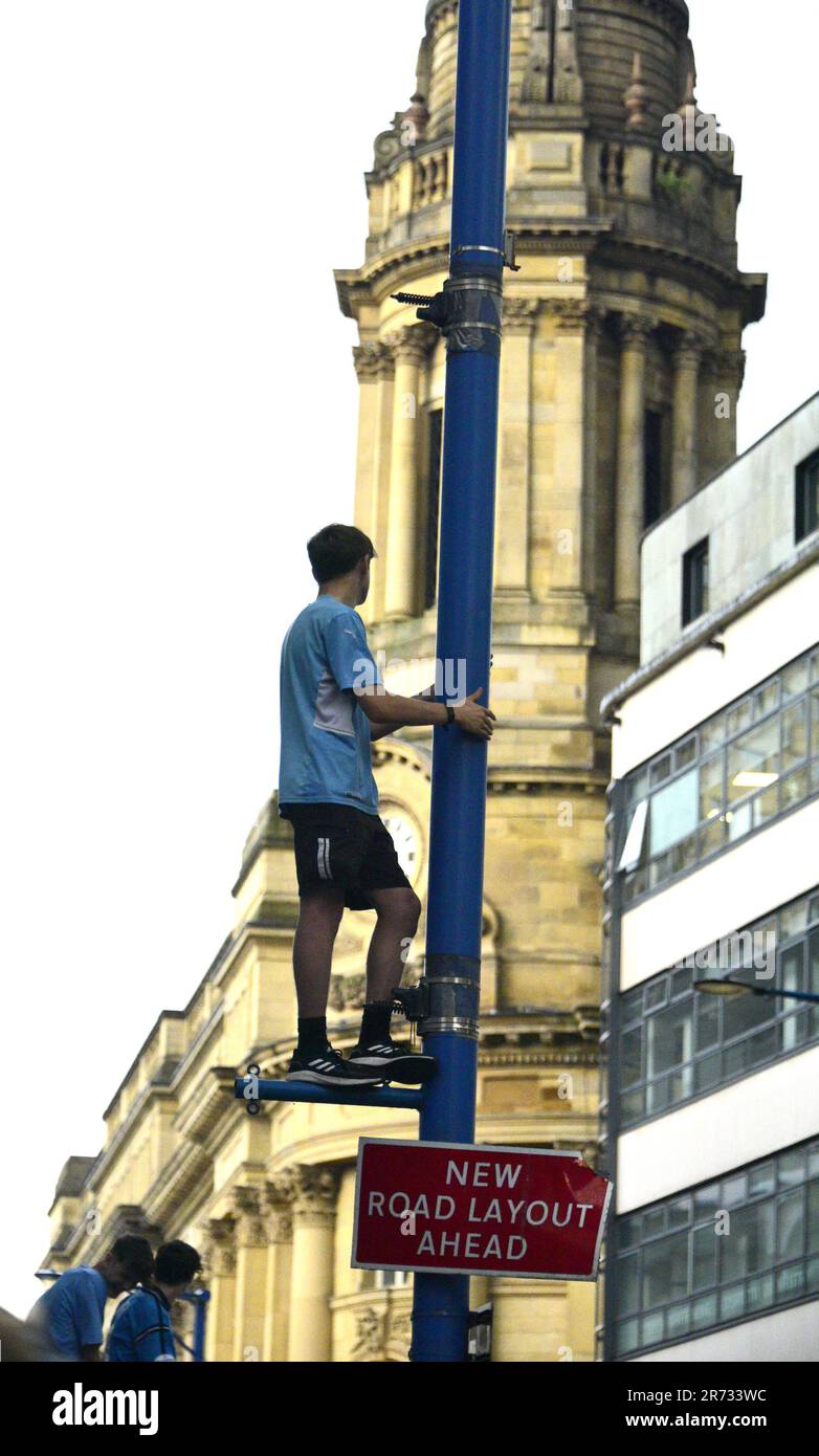 Manchester, UK. 12th June, 2023. A fan climbs street furniture to get a better view as he waits as Manchester City Football Club gets ready to hold an open top bus victory parade in central Manchester, UK, to mark the achievement of winning the treble: the Premier League, the FA Cup, and the Champions League. On Saturday Man City beat Inter Milan in Istanbul to secure the Champions League win. The parade of open top buses went through Manchester city centre watched by large, enthusiastic crowds, despite a thunderstorm and heavy rain. Credit: Terry Waller/Alamy Live News Stock Photo