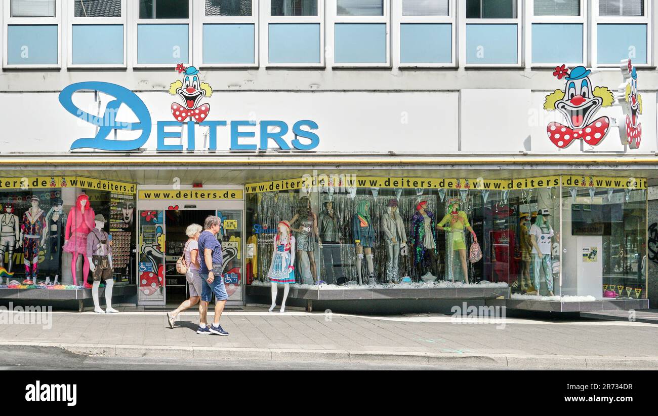 Couple walking past landmark costume shop Deiters in Cologne Germany. Famous for selling outfits for Carnival festival every February. Stock Photo
