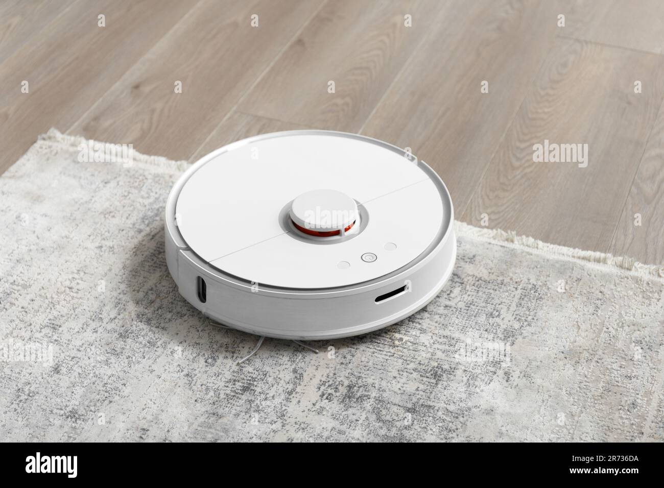 White robot vacuum cleaner on the carpet in the living room near the