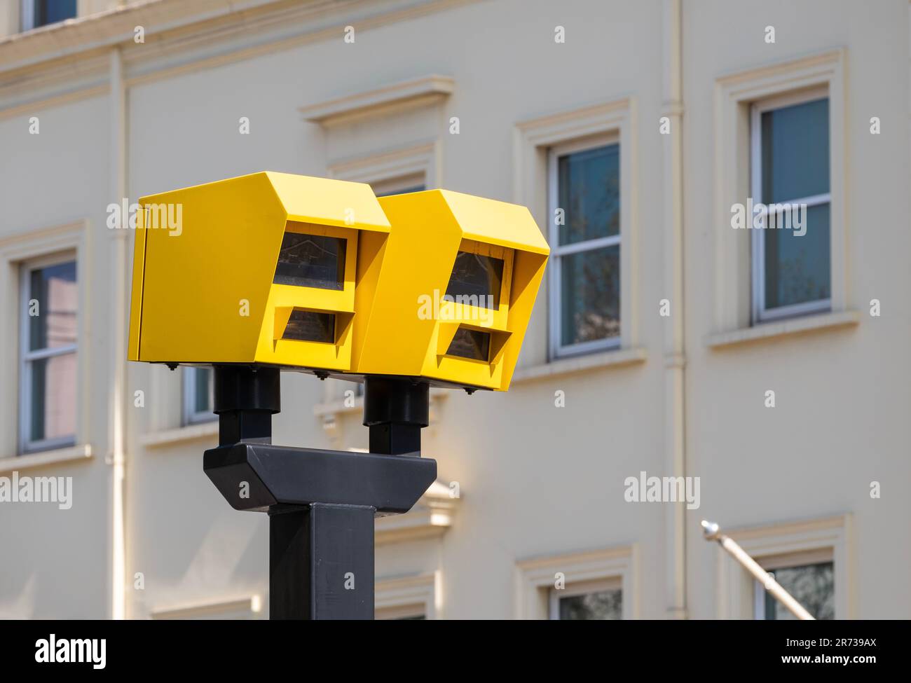 Low angle view of two bright yellow speed safety cameras against an urban background. Stock Photo