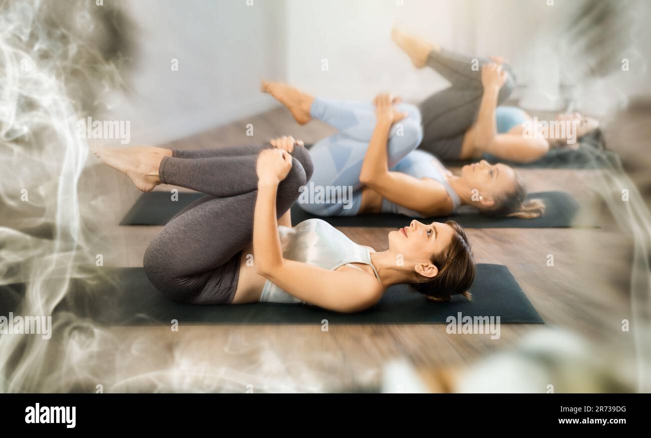 Diligent women practicing wind relieving pose of yoga in light fitness