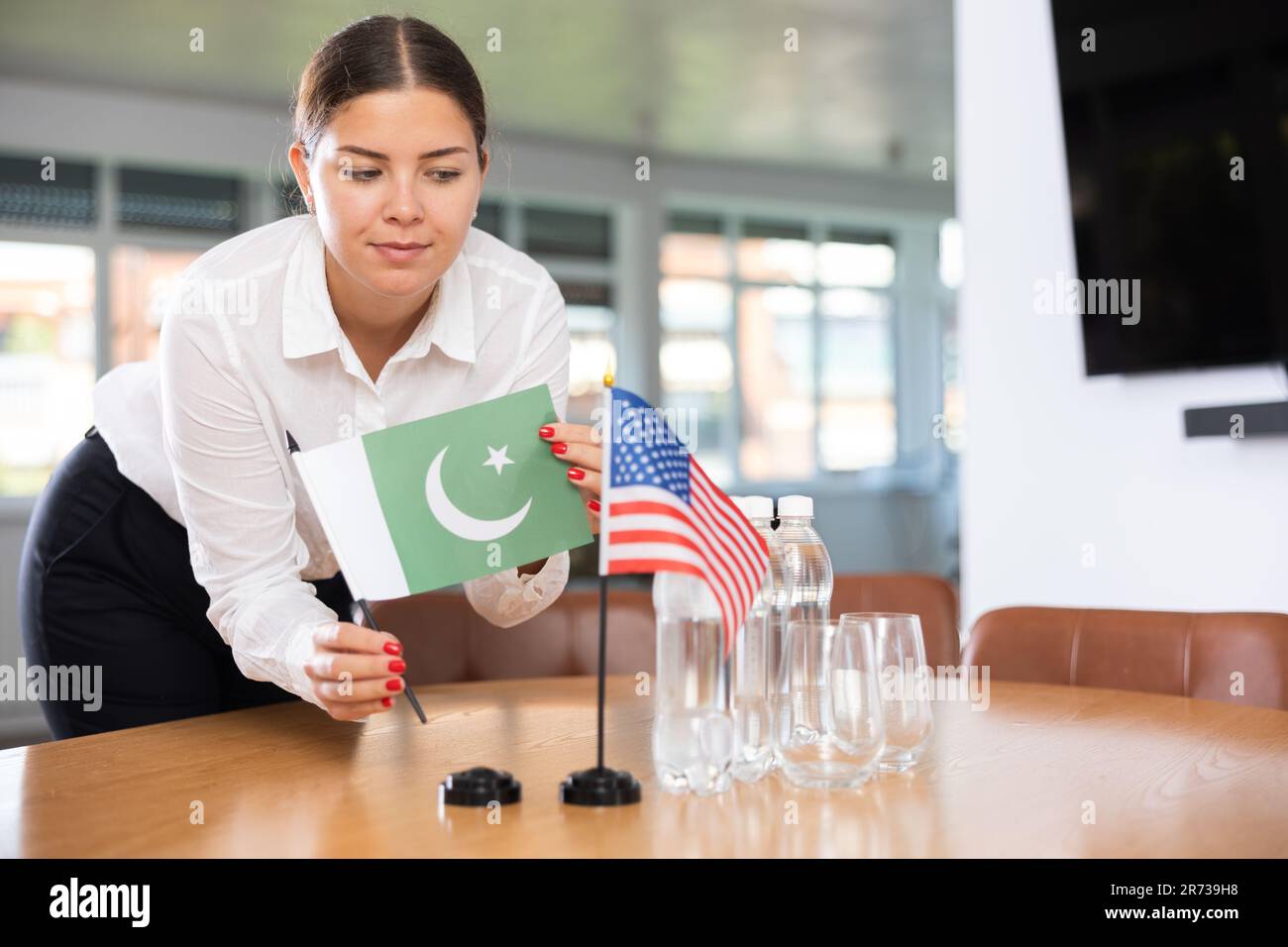 Young woman putting flags of Pakistan and USA on table in office Stock Photo