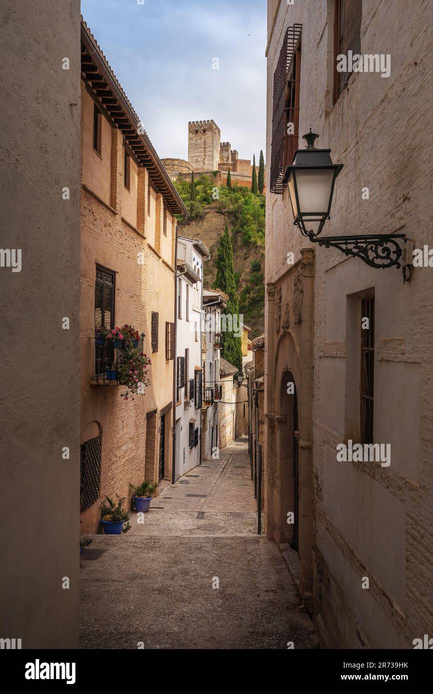 Street of traditional Albaicin district with Alhambra Towers on background - Granada, Andalusia, Spain Stock Photo