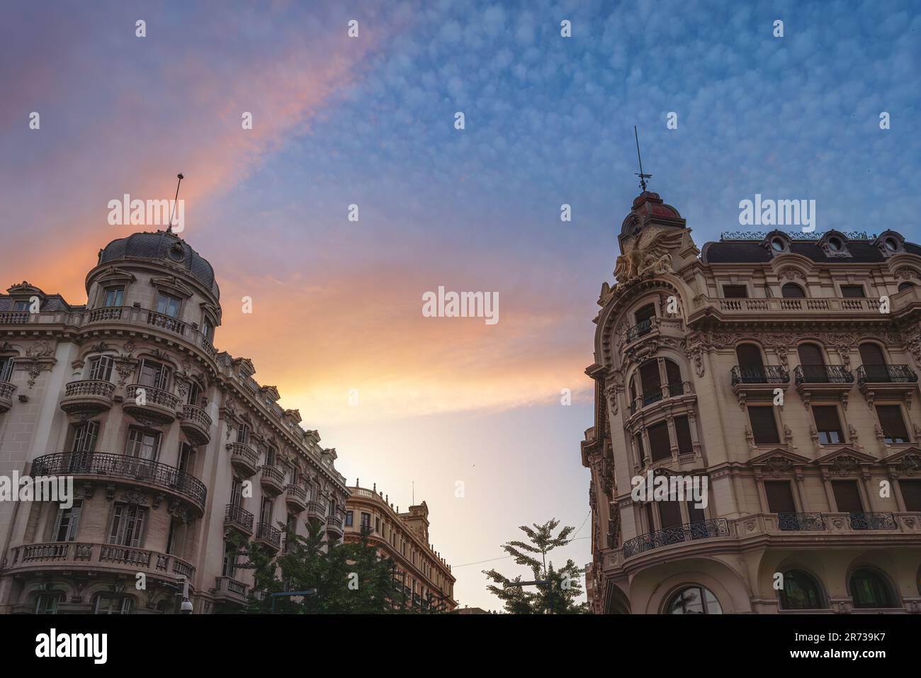 Buildings of Plaza Isabel la Catolica at sunset with former Central Bank - Granada, Andalusia, Spain Stock Photo