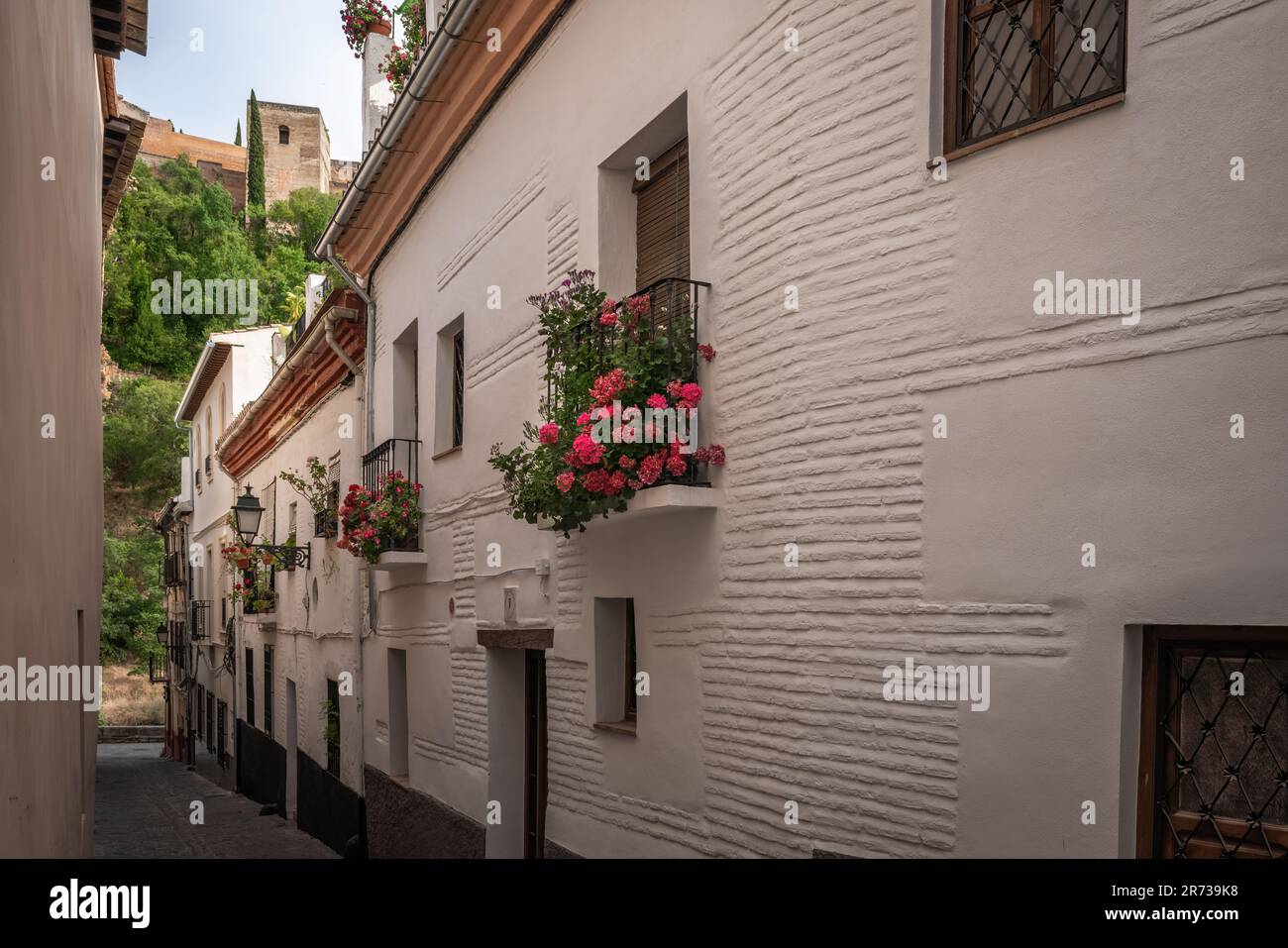 Street of traditional Albaicin district with Alhambra Towers on background - Granada, Andalusia, Spain Stock Photo