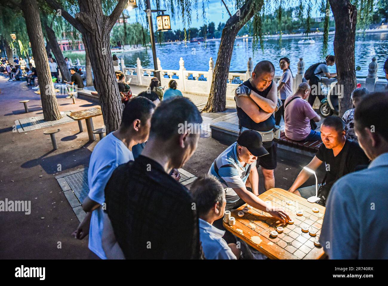 (230613) -- BEIJING, June 13, 2023 (Xinhua) -- People play Xiangqi, or Chinese chess, by Shichahai Lake in central Beijing, capital of China, June 10, 2023. First created in the Yuan Dynasty (1271-1368), the Beijing Central Axis, or Zhongzhouxian, stretches 7.8 kilometers between the Yongding Gate (Yongdingmen) in the south of the city and the Drum Tower and Bell Tower in the north. Most of the major old-city buildings of Beijing sit along this axis.Fourteen historical places along the axis, including Qianmen, the Forbidden City, Jingshan Park, the Drum and Bell Towers, and Tian'anmen Square h Stock Photo