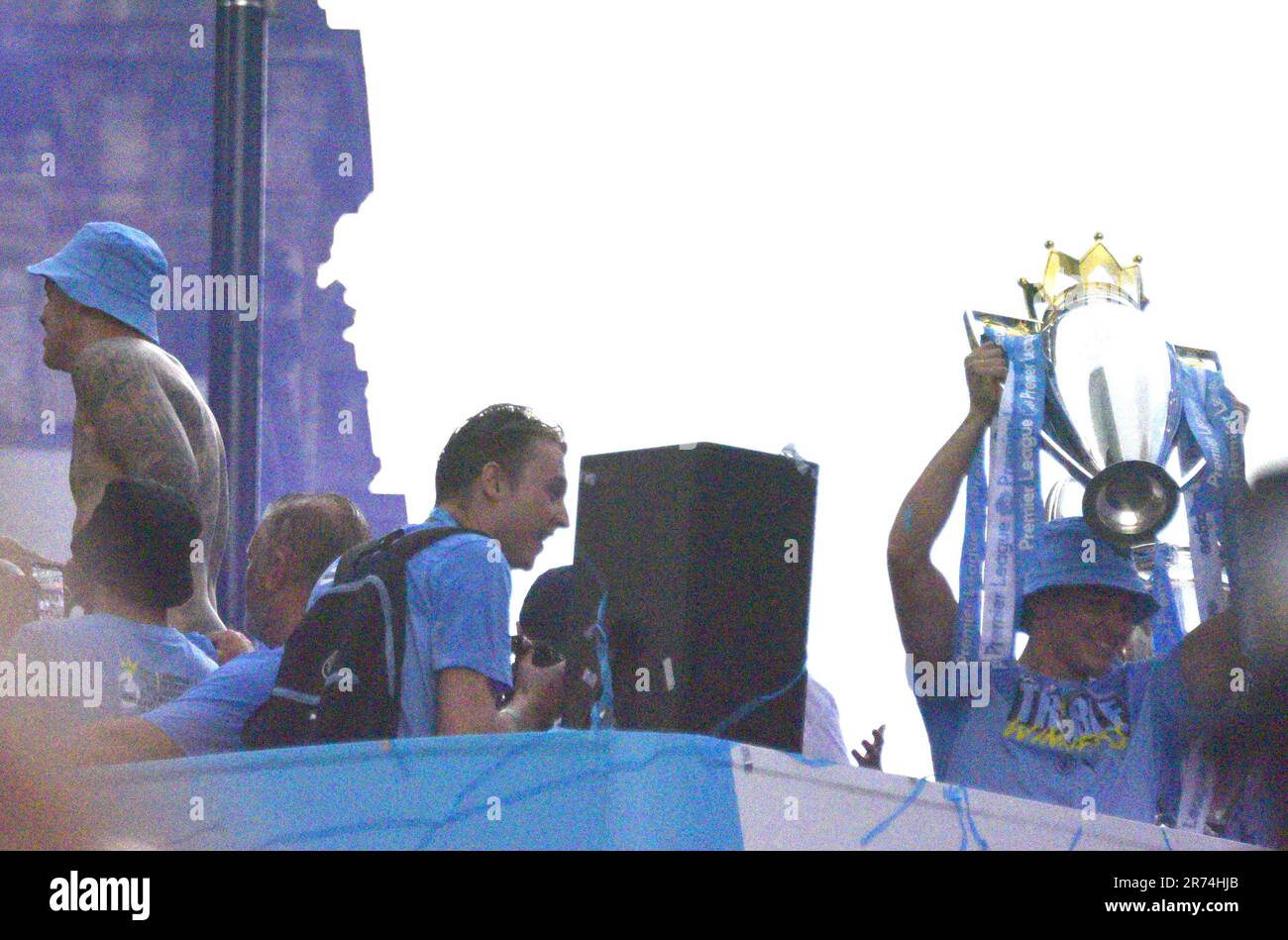 Manchester, UK. 12th June, 2023. The cup held high on the open top bus. Open top bus victory parade celebration in central Manchester, UK, to mark the achievement of their club winning the treble: the Premier League, the FA Cup, and the Champions League. On Saturday Man City beat Inter Milan in Istanbul to secure the Champions League win. The parade of open top buses went through Manchester city centre watched by large, enthusiastic crowds, despite a thunderstorm and heavy rain. Credit: Terry Waller/Alamy Live News Stock Photo