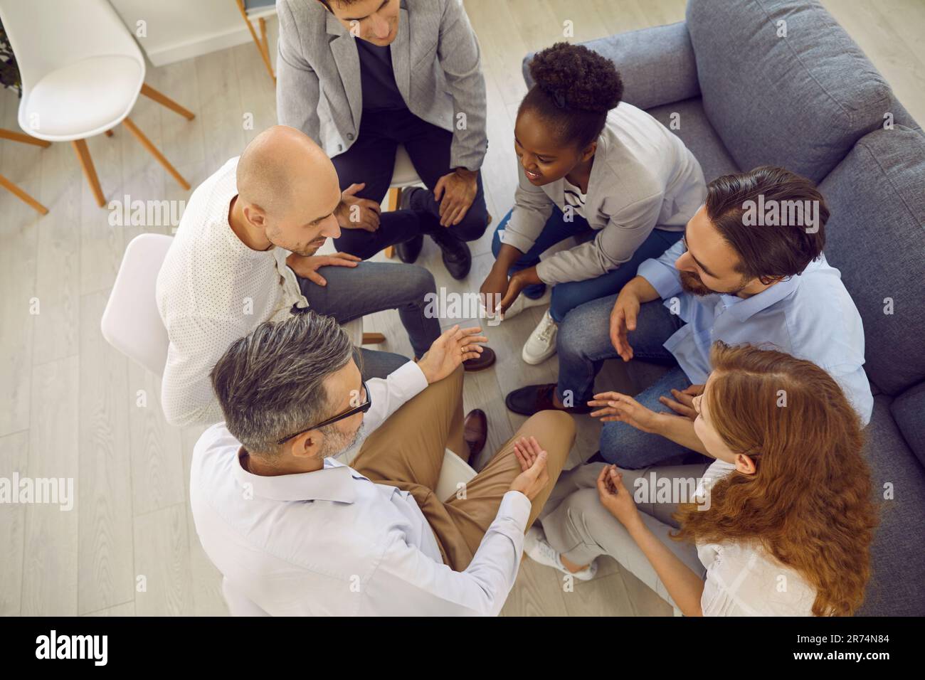 Multiracial people sit in circle talking together in psychological group on therapy session. Stock Photo
