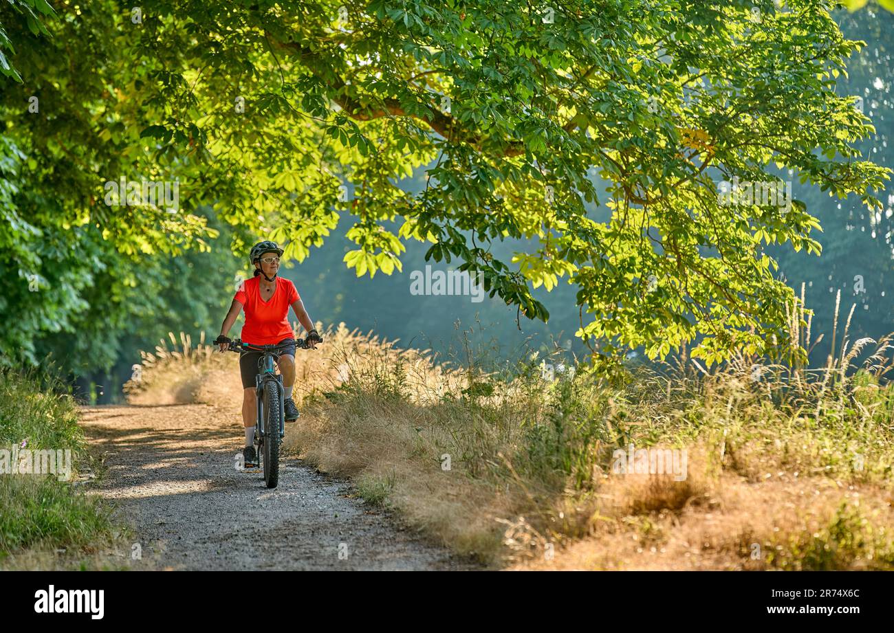 attractive senior woman cycling with her electric mountain bike in the city park of Stuttgart, Baden-Wuerttemberg, Germany Stock Photo