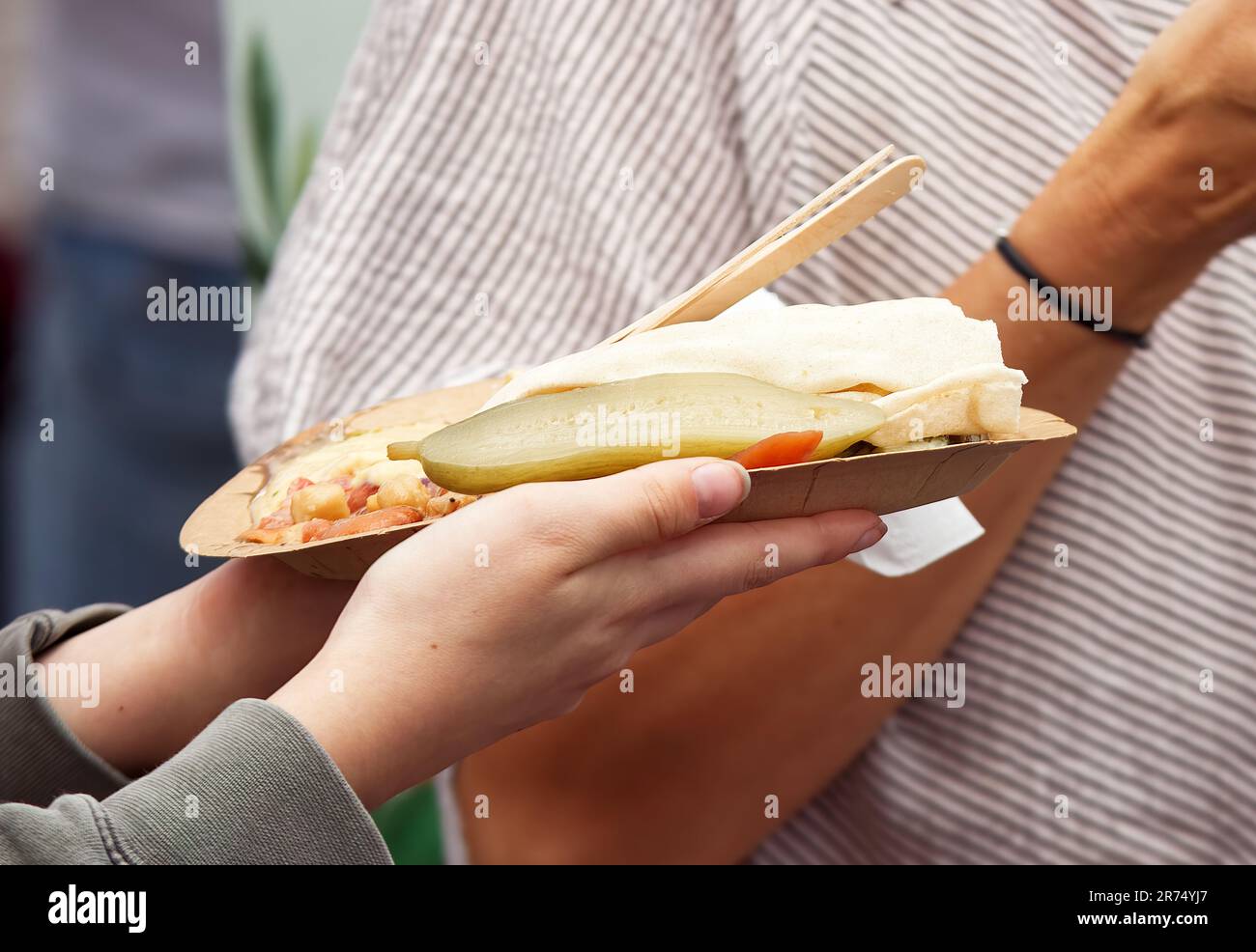 Farmers market visitor holds a paper tray with refreshment, pickles and