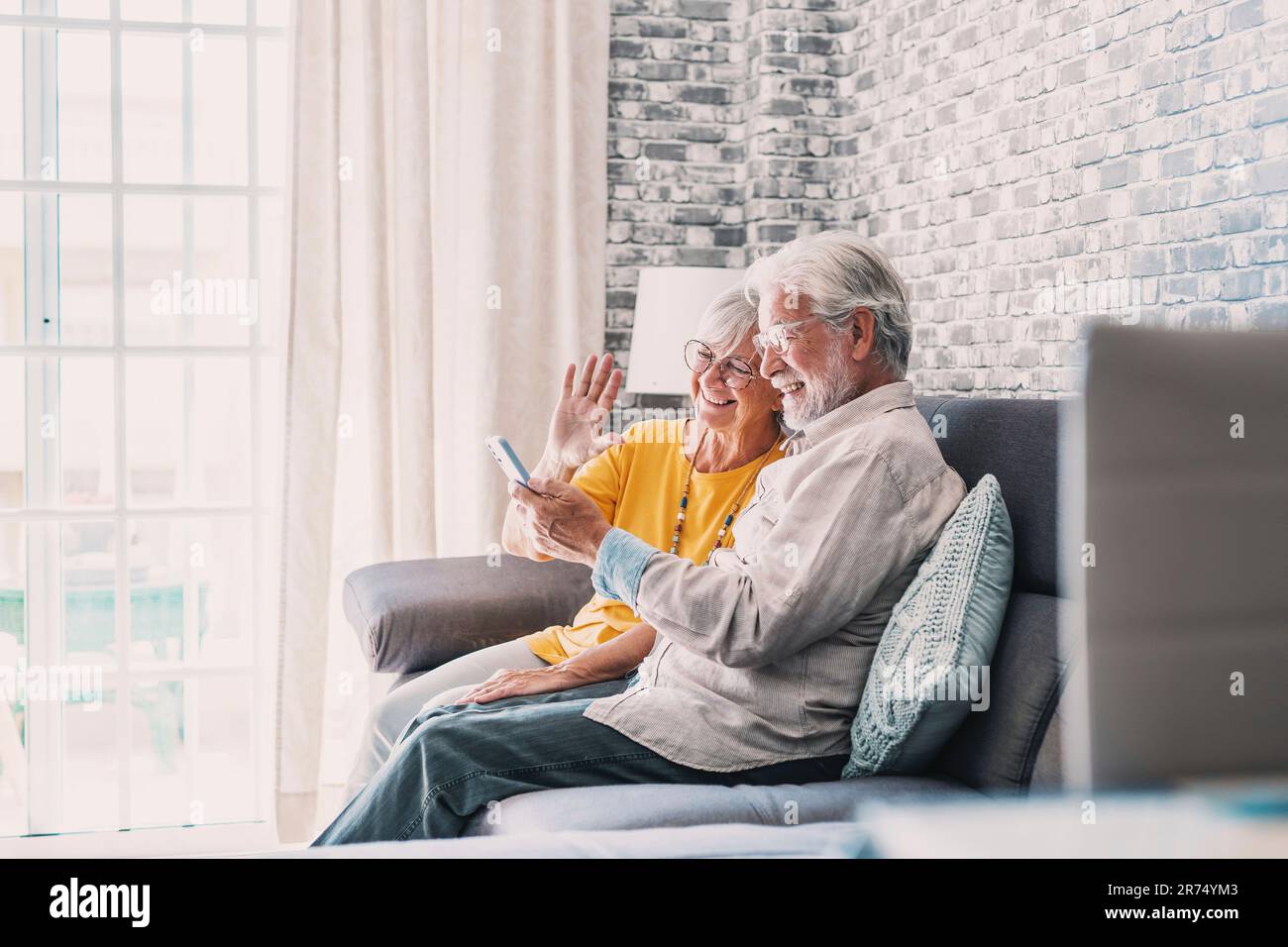 Happy retired family couple using mobile phone for video call together, talking to relations, getting good news, having fun, smiling and laughing. Carefree mature pensioners chatting online on cell Stock Photo