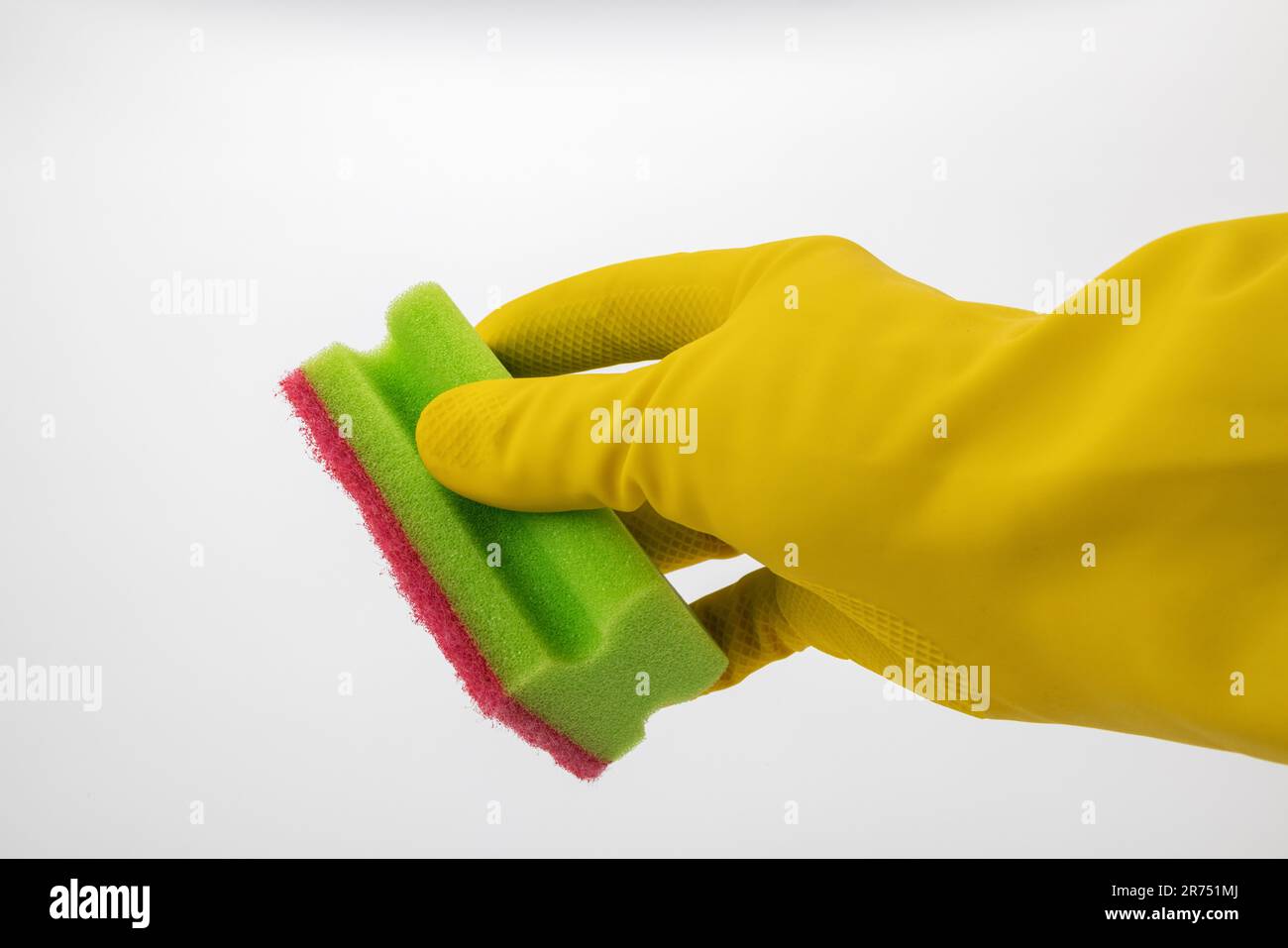 Hand with yellow protective glove holds cleaning sponge with handle green-red, white background, Stock Photo