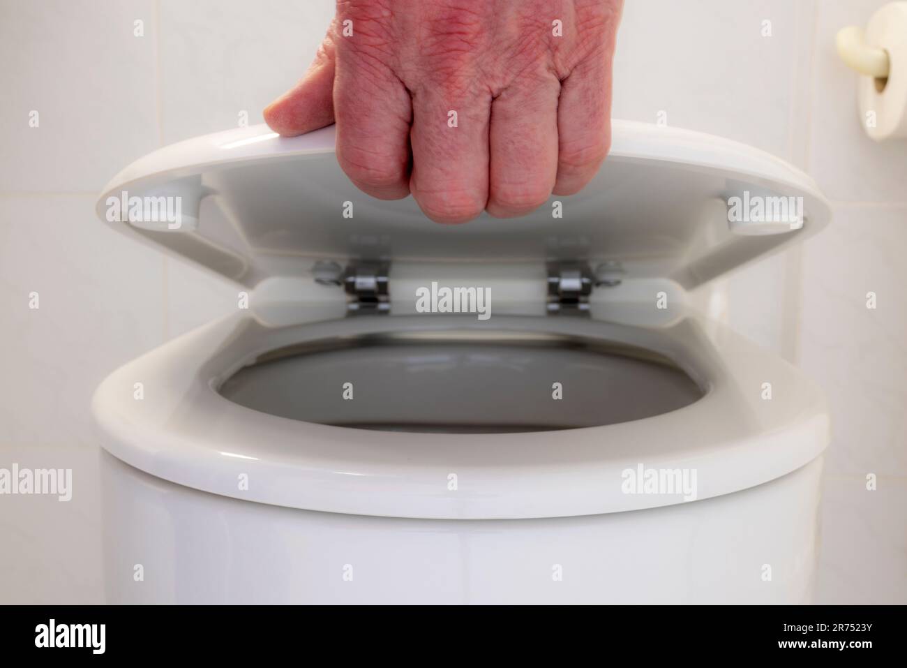 Man hand lifts toilet lid, toilet walk Stock Photo Alamy