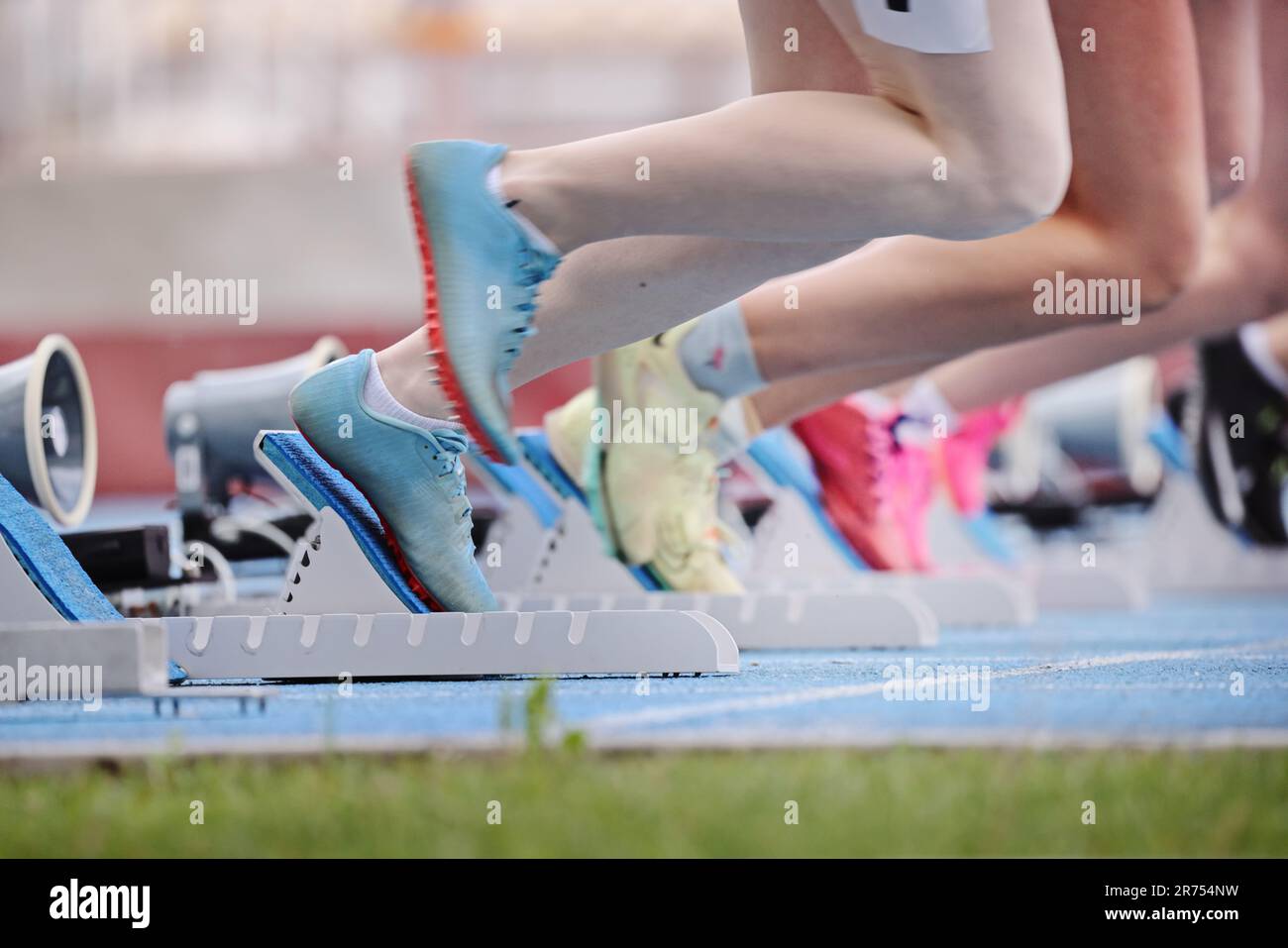 Athletes beginning a race on starting blocks at a running track Stock