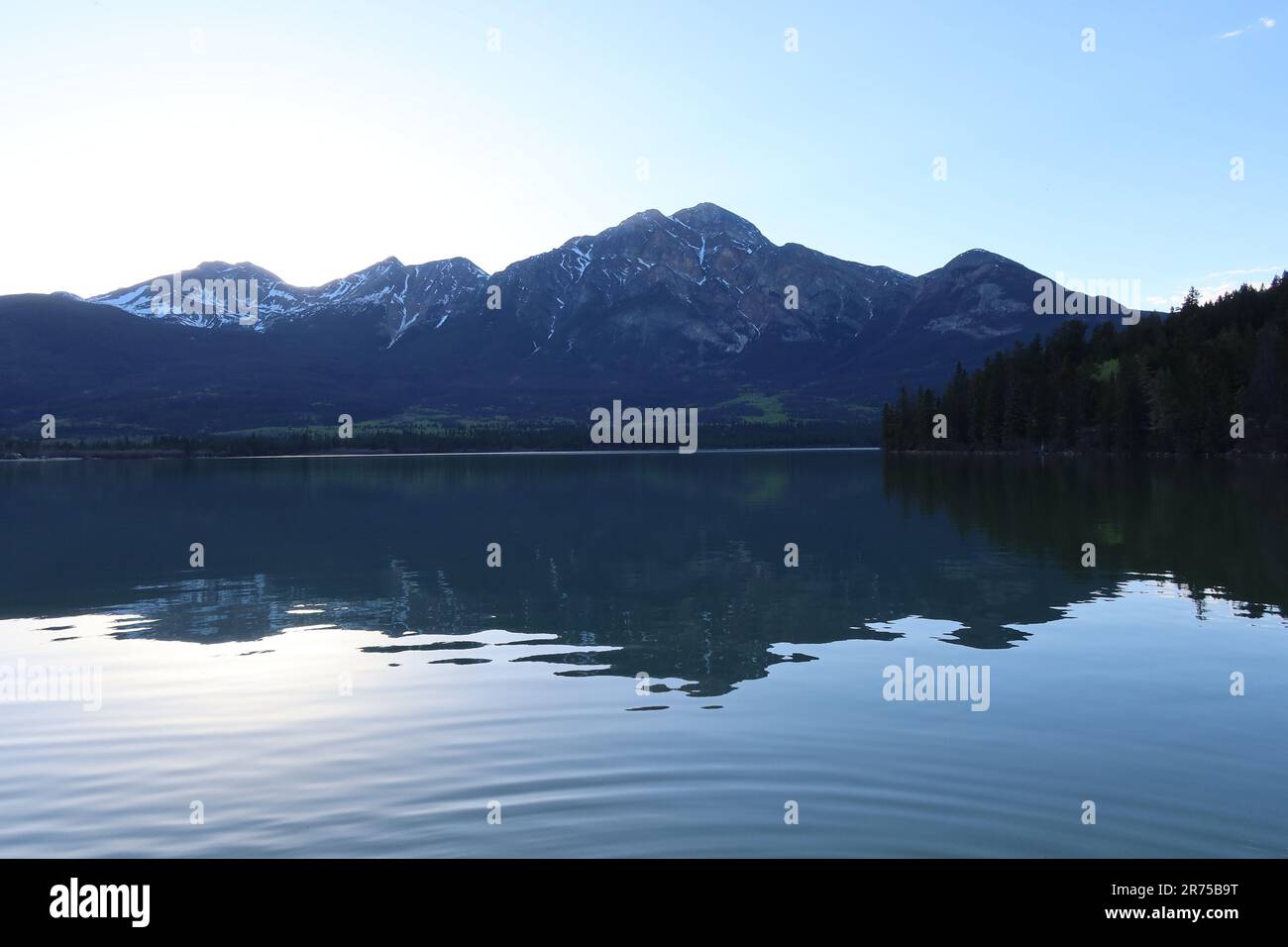 A scenic view of a majestic lake surrounded by towering mountain peaks ...