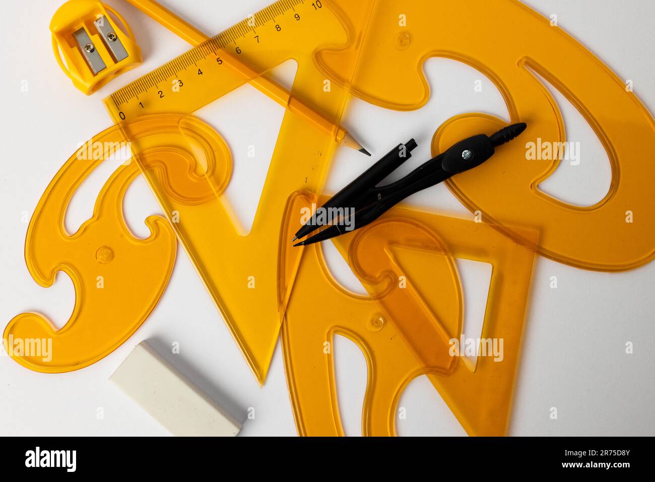 Close up of yellow rulers, compass and sharpener on white background ...