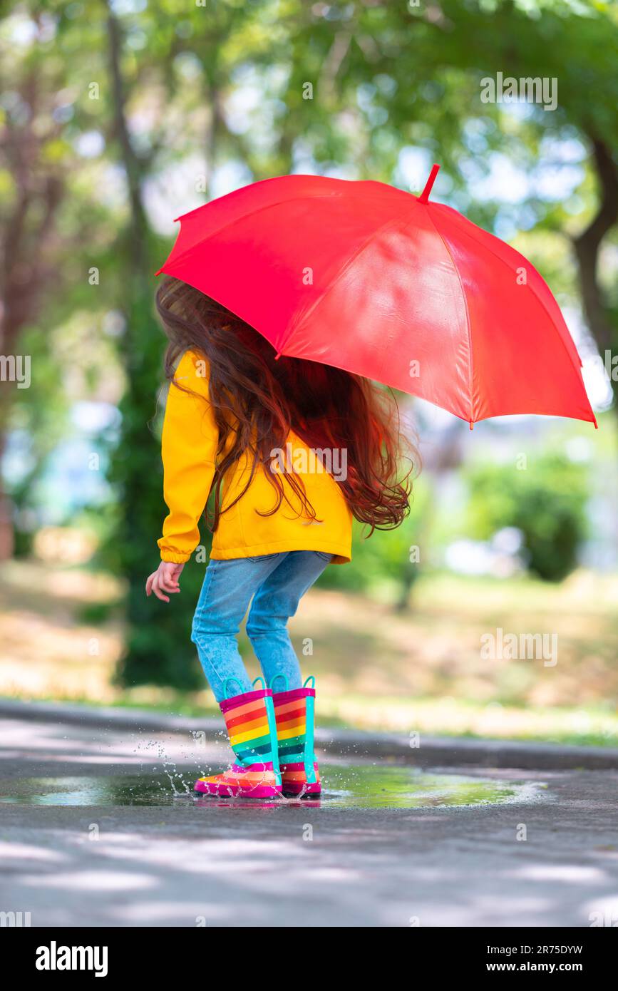Happy beautiful girl with umbrella and color rubber boots jump on a ...