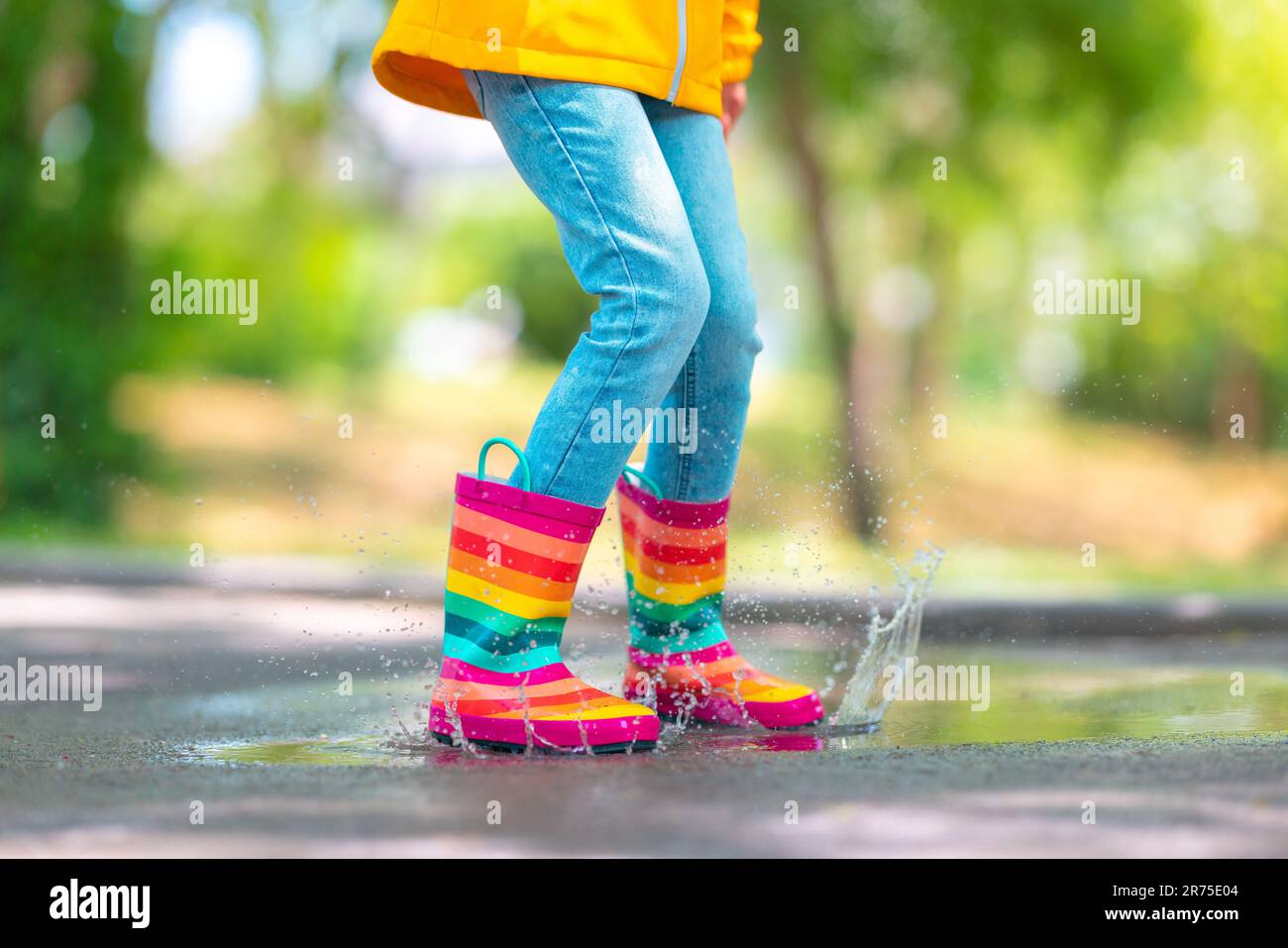 Feet of child in colorful rubber rain boots jumping over rainy puddle in a park Stock Photo Alamy