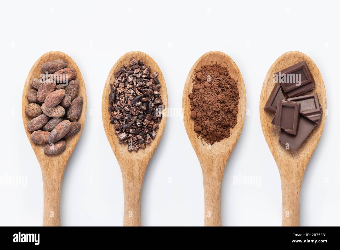 Chocolate bar, cocoa powder, cacao beans and nibs, heap in wooden spoons, chocolate background Stock Photo