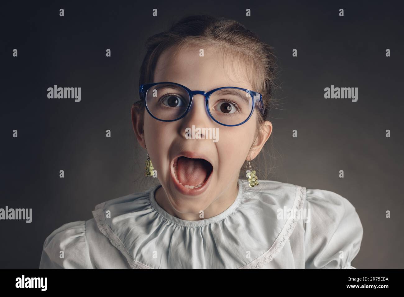 Beautiful clever, little girl with glasses, studio portrait on black background. Smart preschooler, doctor or teacher Stock Photo