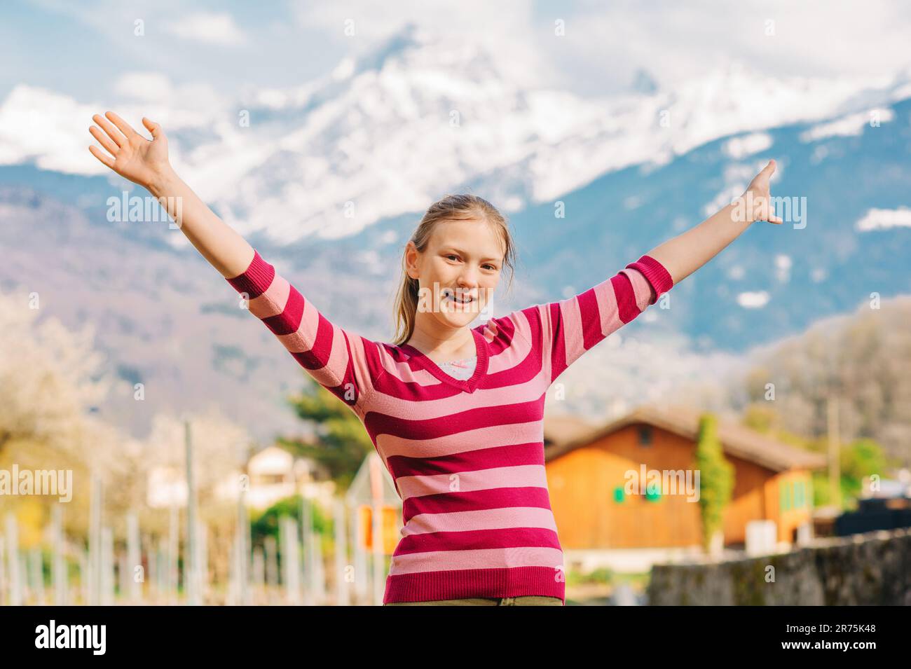 Outdoor portrait of happy young teenage girl hiking in mountains, arms