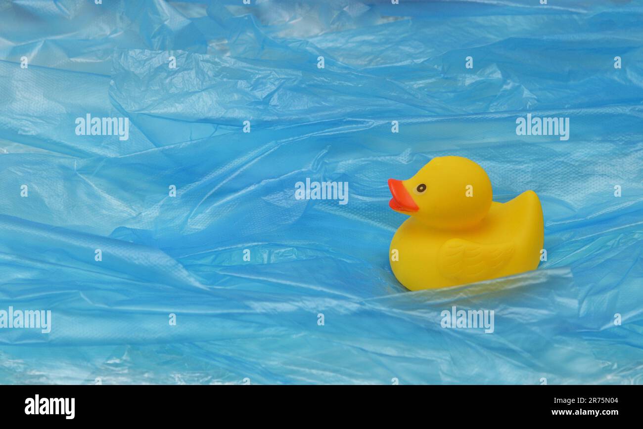 Concept Pollution Plastic In Sea with Yellow Rubber Duck Toy and Plastic Waves Stock Photo
