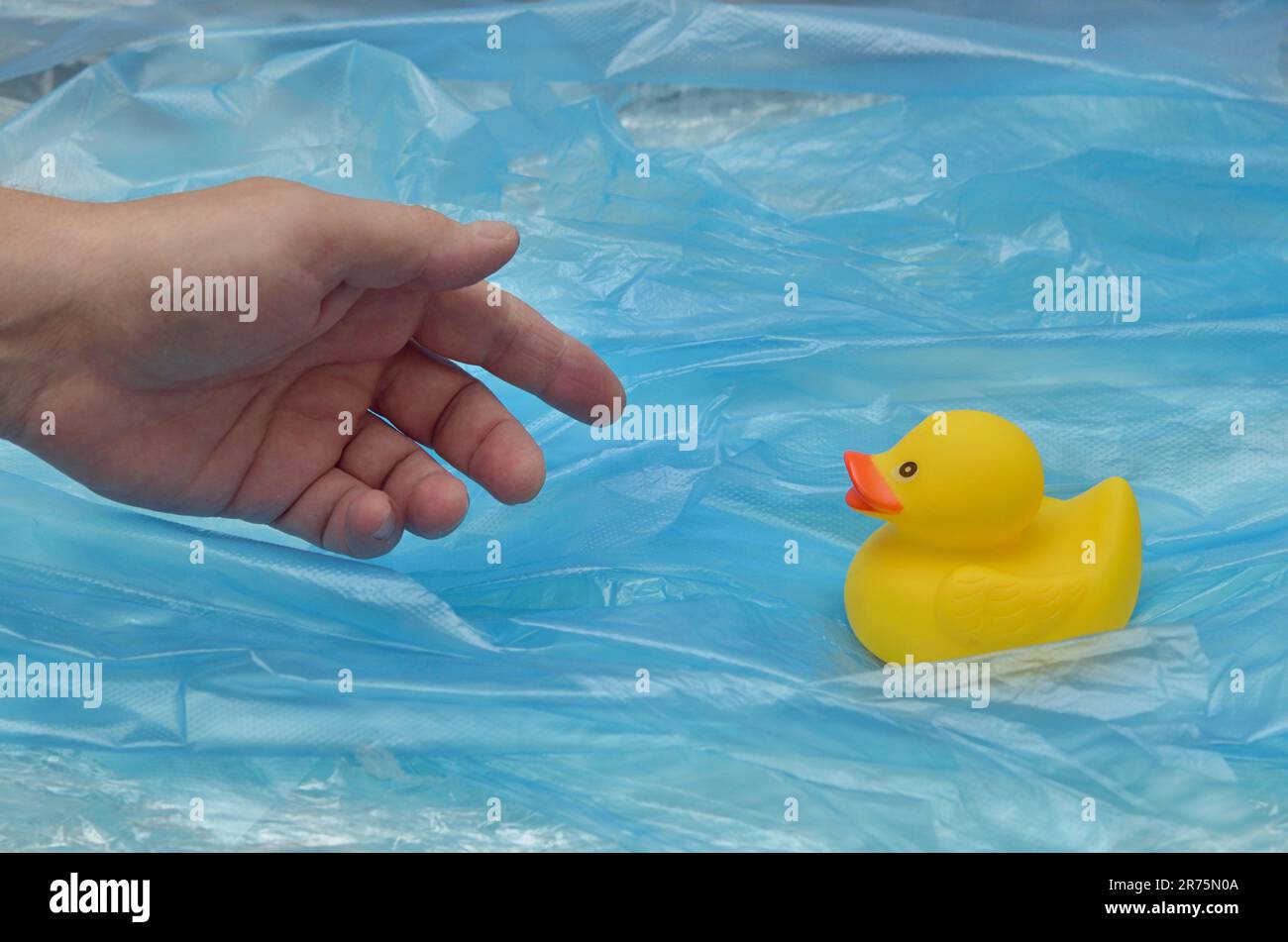 Concept Pollution Plastic In Sea with Yellow Rubber Duck Toy and Man Hand Stock Photo