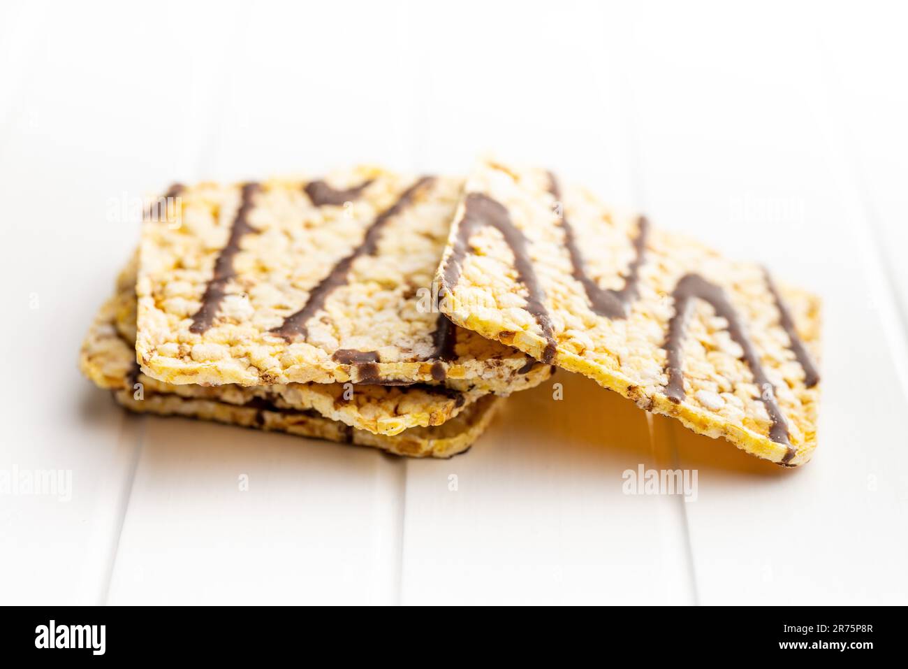 Puffed corn crackers chocolate covered on the white table. Stock Photo