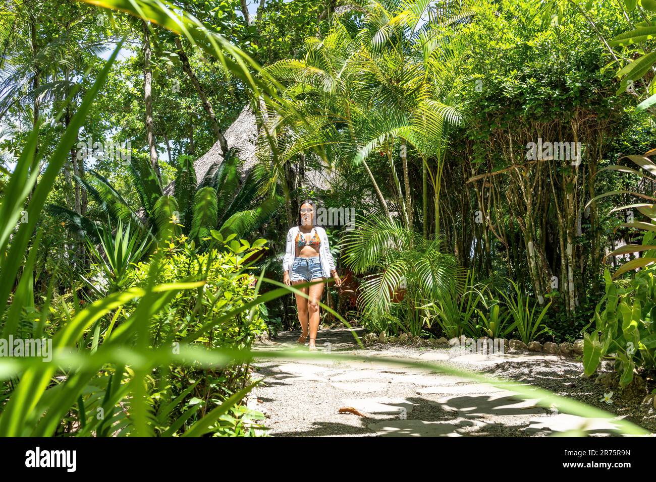 North America, Caribbean, Greater Antilles, Hispaniola Island, Dominican Republic, North Coast, Puerto Plata Province, Cabarete, Attractive Latina Walks a Path in Boutique Hotel Natura Cabana Along Stock Photo