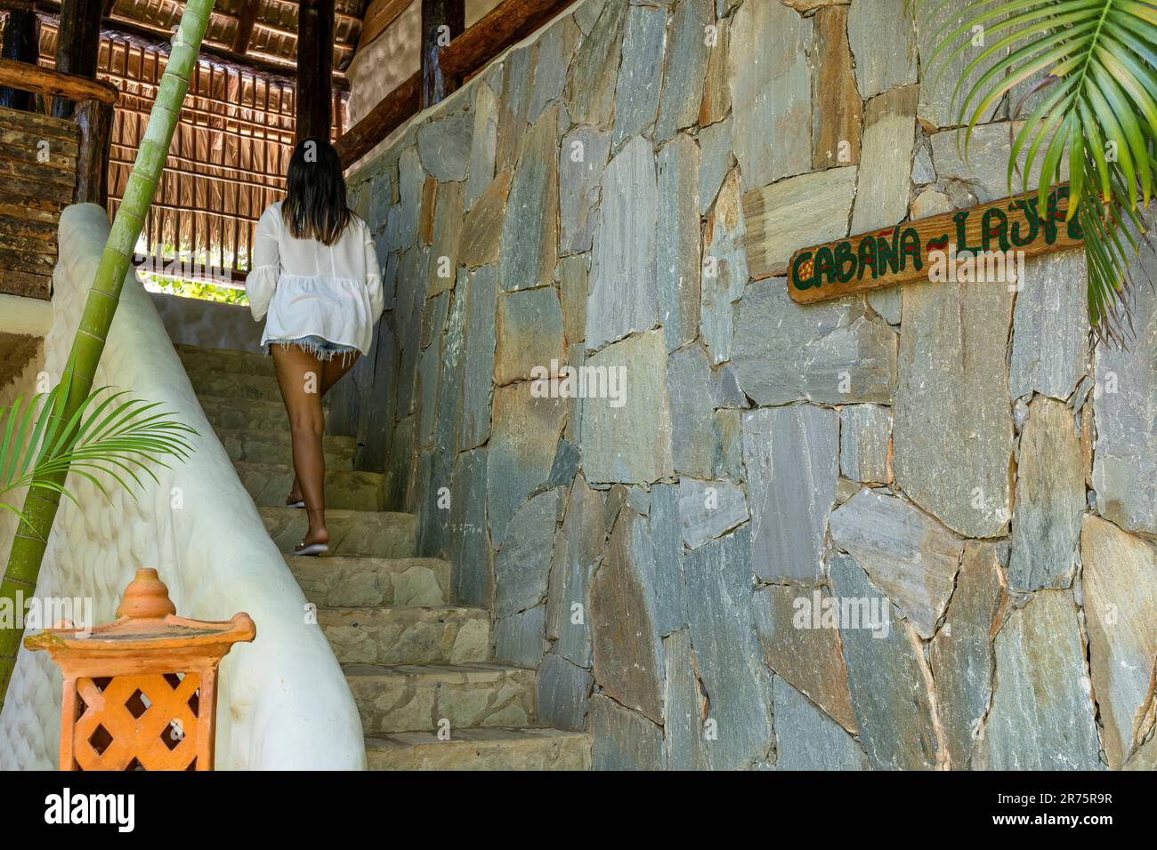 North America, Caribbean, Greater Antilles, Hispaniola Island, Dominican Republic, North Coast, Puerto Plata Province, Cabarete, Young woman climbing the stairs to her bungalow at Boutique Hotel Natura Cabana Stock Photo