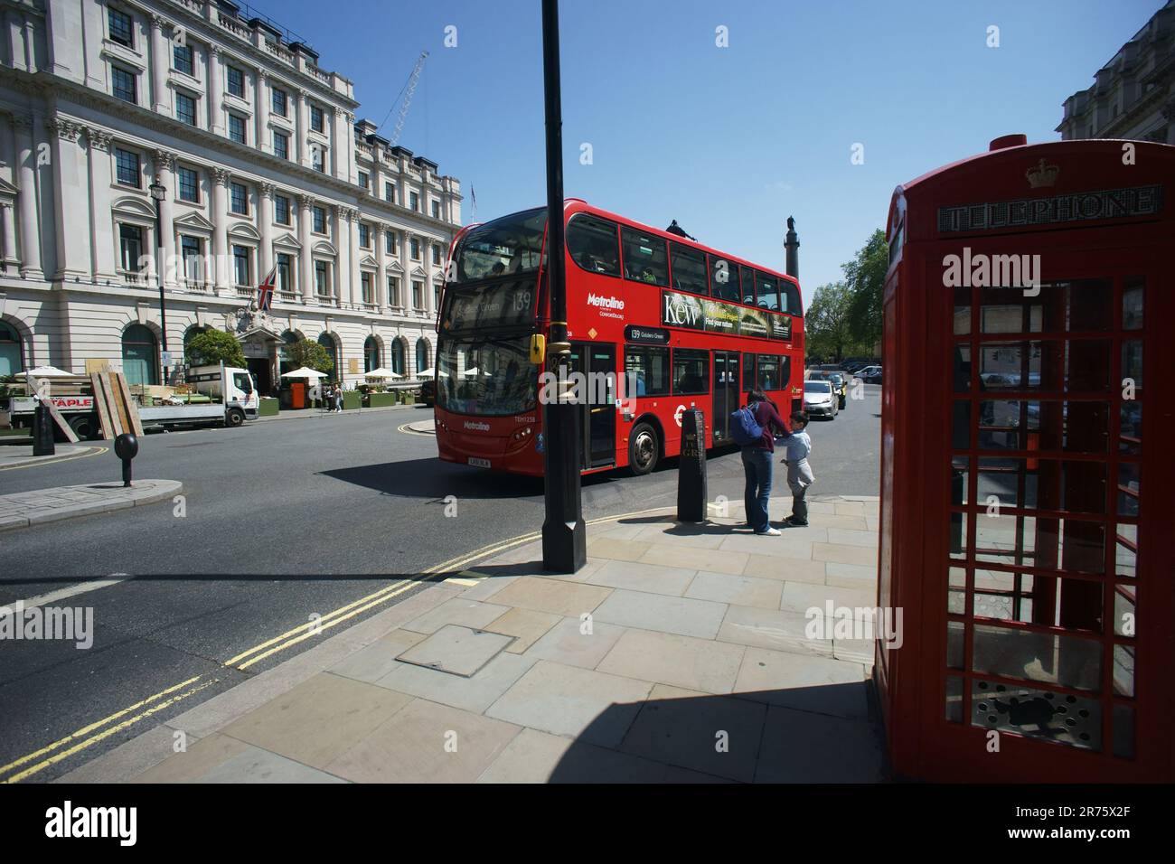 Iconic London - a red bus passes one traditional red telephone boxe in central London UK Stock Photo