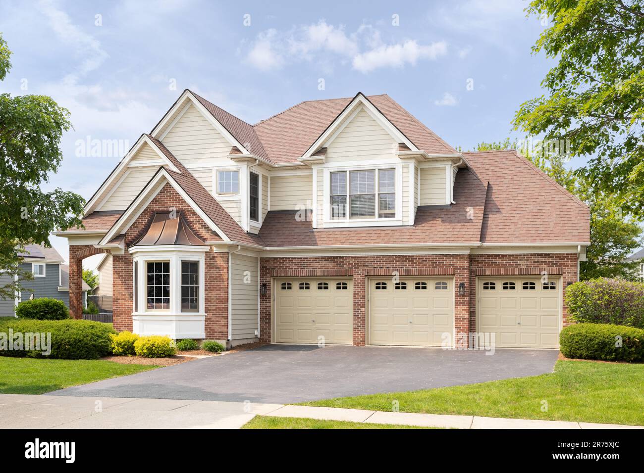 A large home with a red brick and yellow siding, three car garage, and ...