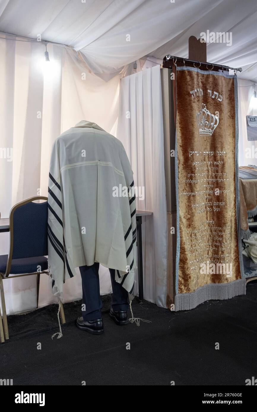 An anonymous older orthodox Jewish man wearing a talis bows his head