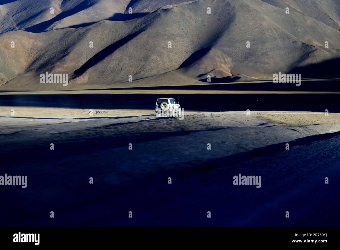 A white van drives through a rural landscape, with a majestic mountain ...