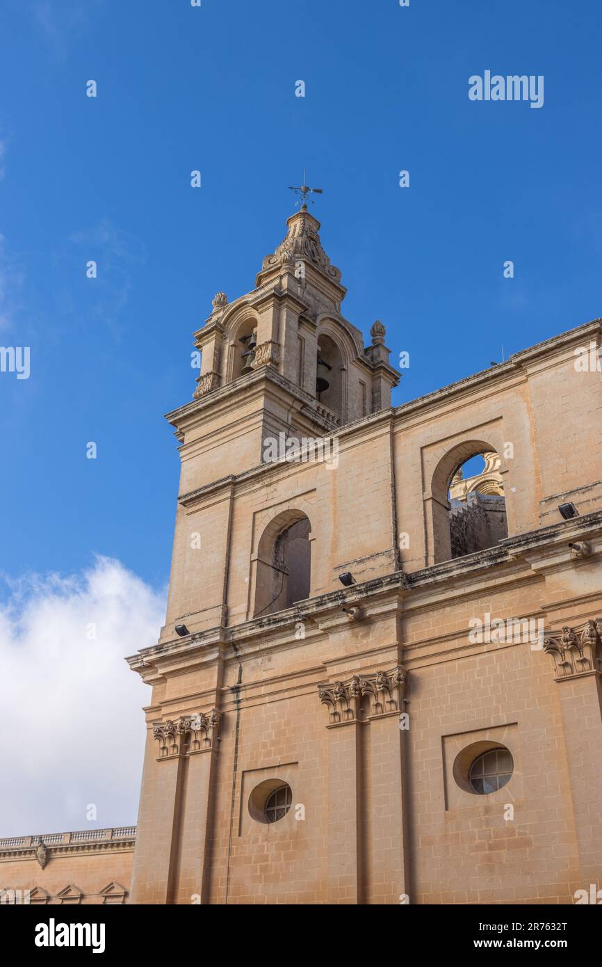 An antiquated stone church featuring a grand tower and glistening windows in Mdina Old City Fortress Stock Photo