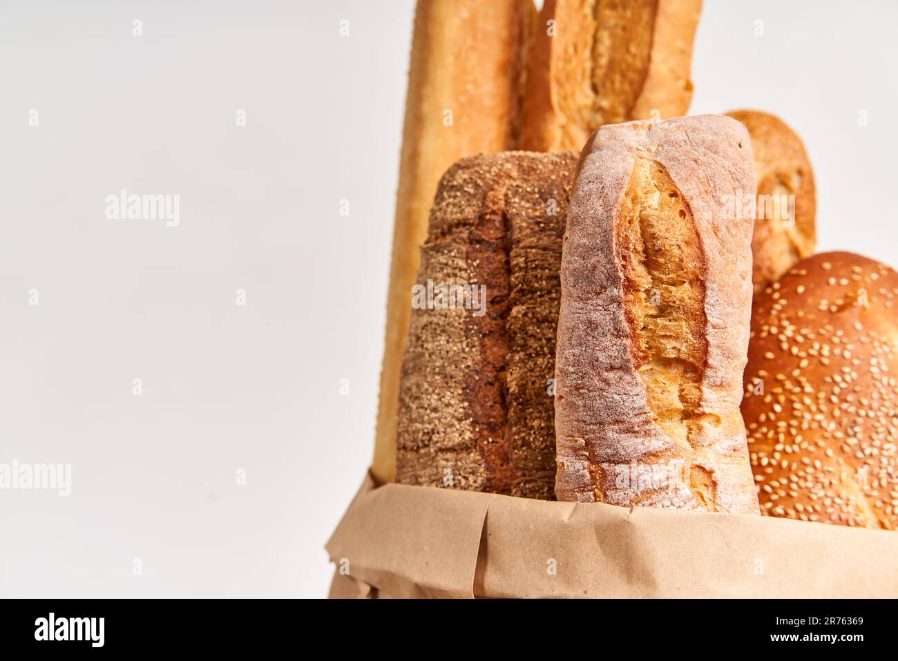Different types of french bread baguettes in paper bag over white ...