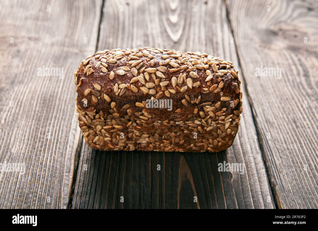 Loaf of fresh made rye multigrain bread on wooden table background. Bakery, food concept Stock Photo