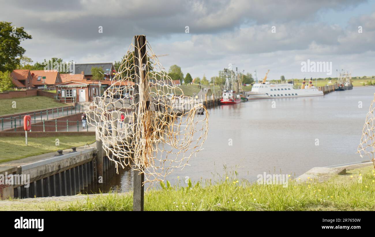 Black Cross with a fishing net in the Harbor of Greetsiel as a silent protest by the fishermen against a planned ban of bottom trawls Stock Photo