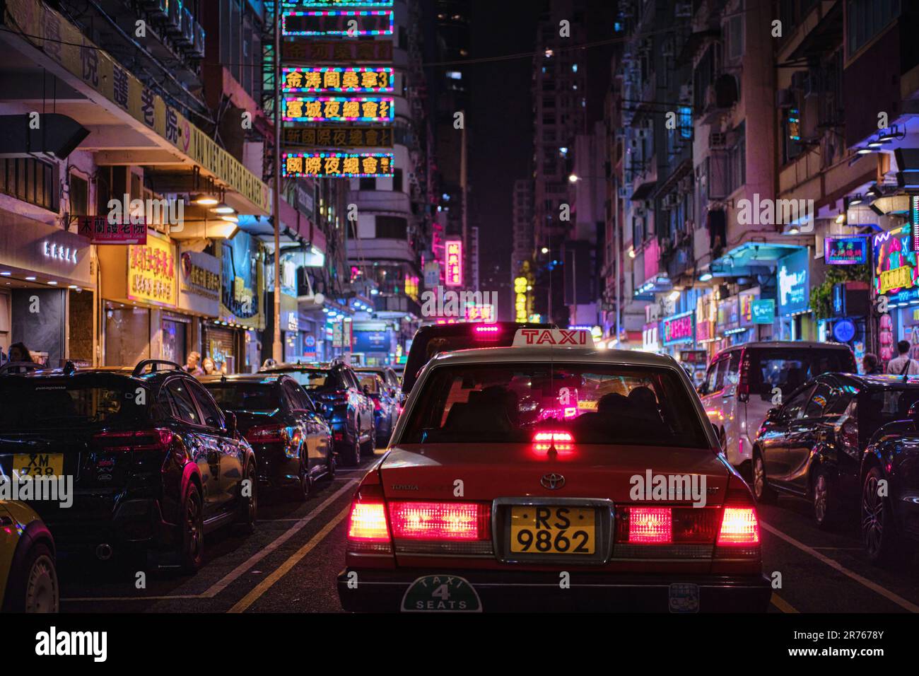 Mong Kok, Hong Kong - April 12 2023: A Traditional red Taxi and colorful neon light signs Stock Photo