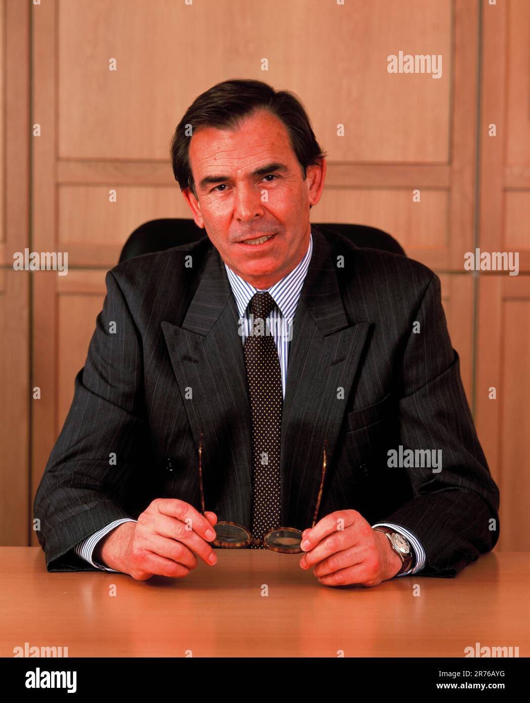 Business executive man indoors sitting at his office desk. Stock Photo