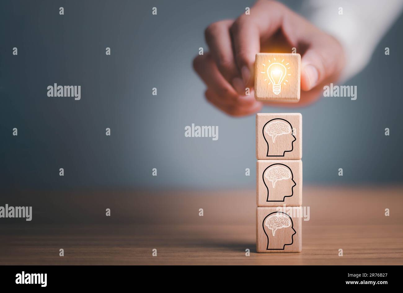 brainstorming creative idea and innovation. Hand putting over wooden cube block with light bulb icon on many people together having an idea symbolized Stock Photo